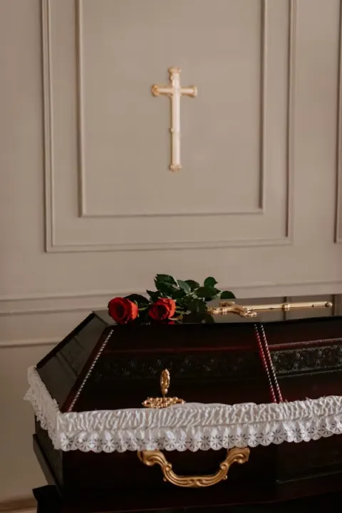 Sicriu cu doi trandafiri roșii și o cruce aurie